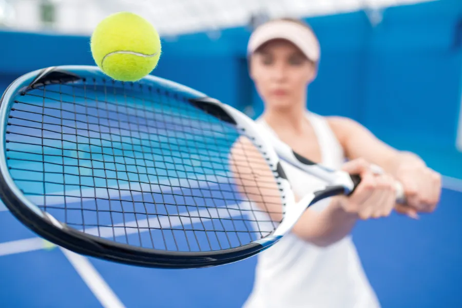 Woman swinging racket at tennis ball